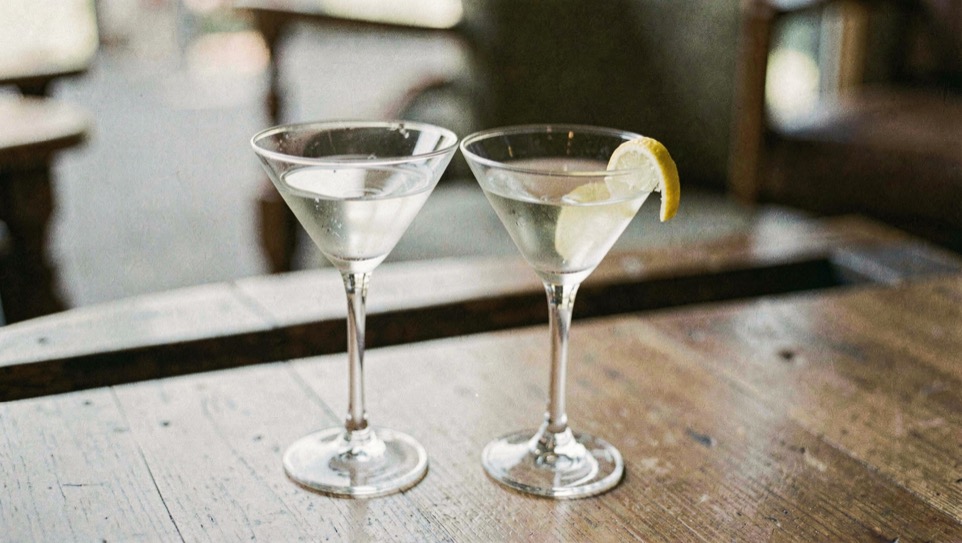 A clear martini in a coupe beside a lemon twist